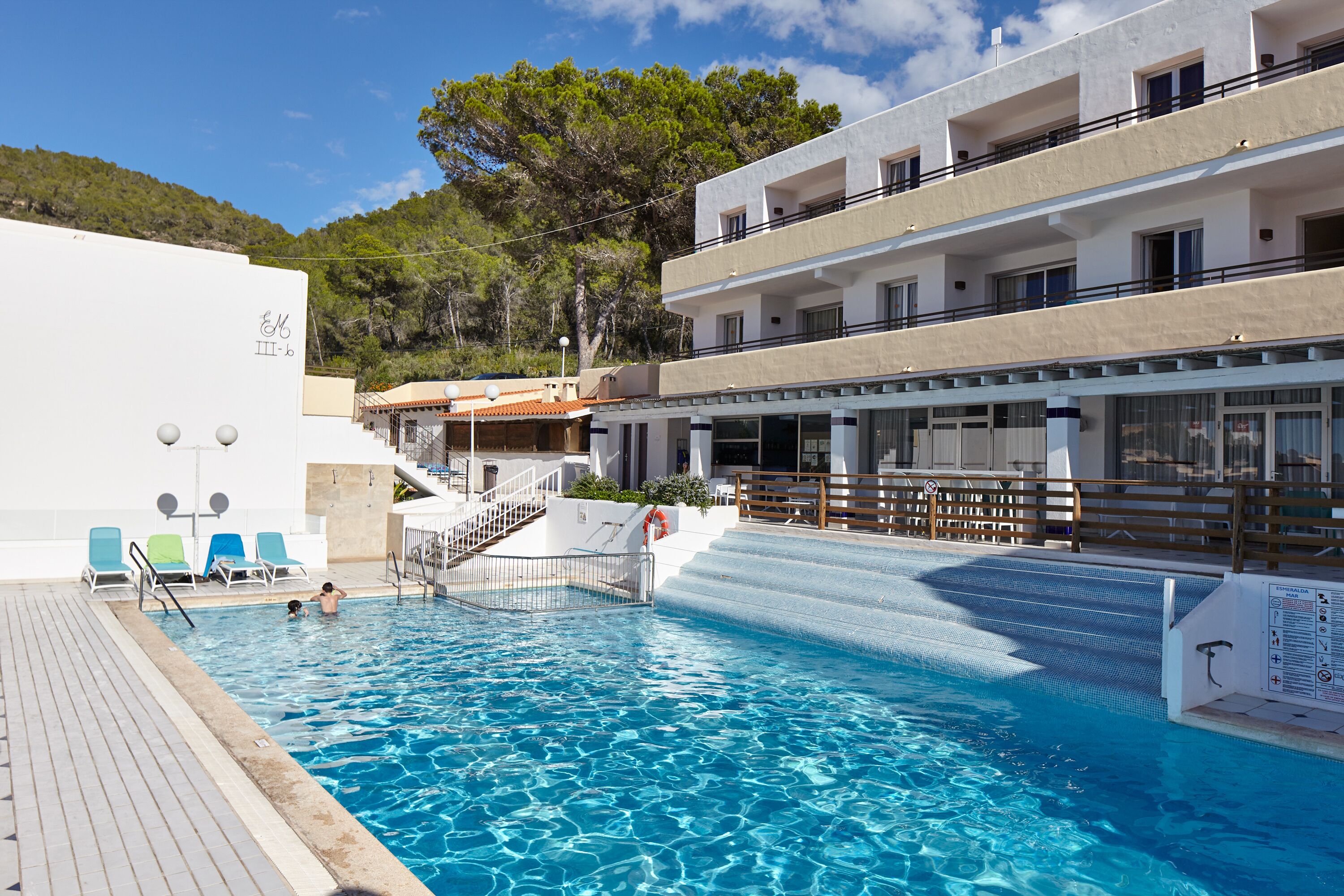 A swimming pool with a wooden deck, a lifeguard chair, and a sign indicating pool depth.