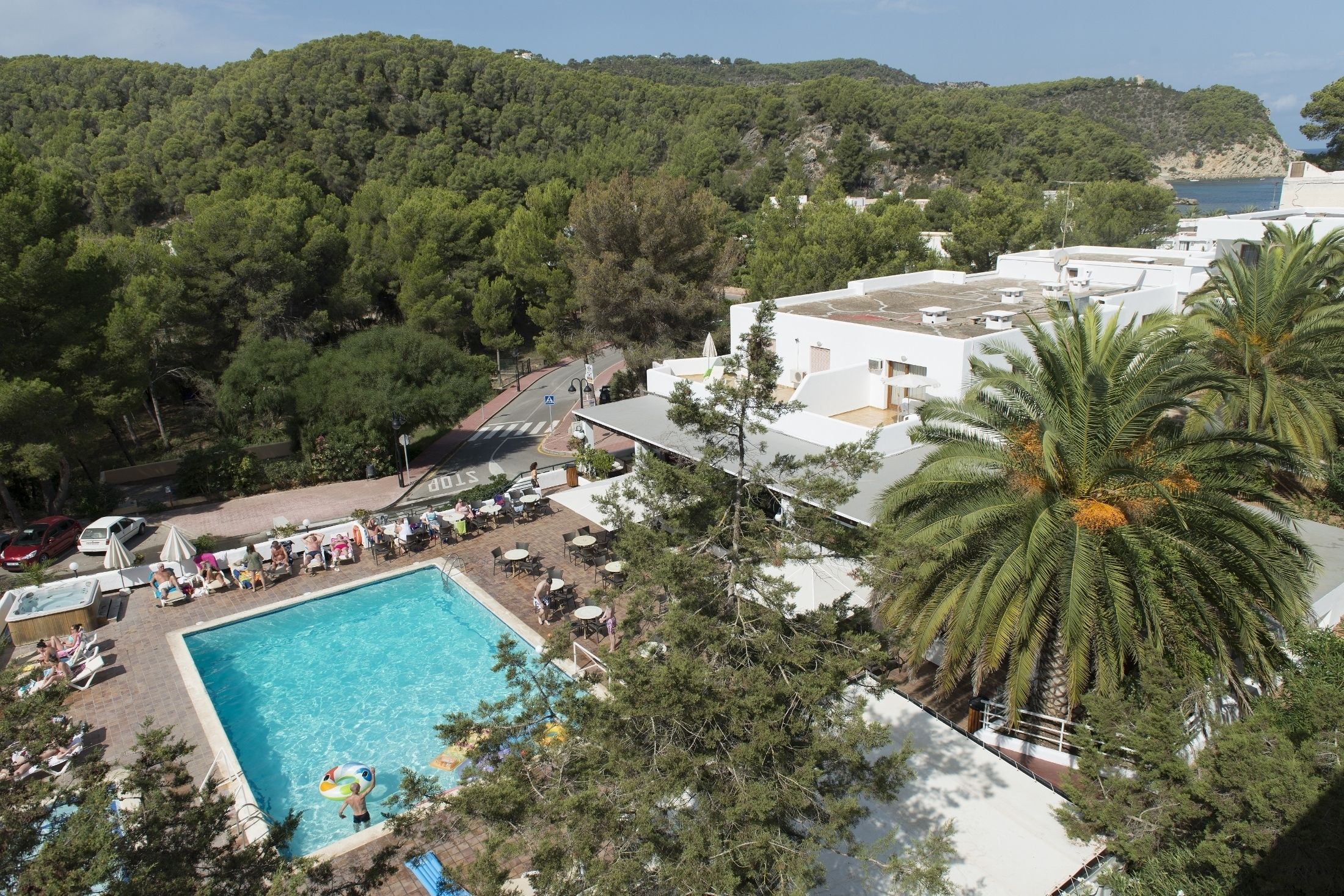 A pool area with lounge chairs and umbrellas, surrounded by trees and buildings.