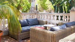 A wicker outdoor seating area with cushions, a small round table, and a potted plant. - 4U Miranda - Adults Only (Calvia)