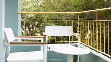 A balcony with two white chairs and a small table, surrounded by a yellow railing.