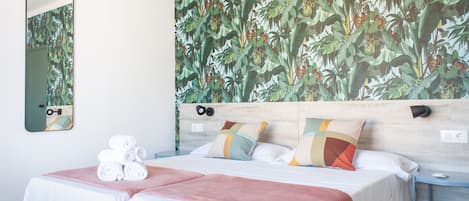 Una camera d'albergo con un letto, un comodino, uno specchio e una parete decorata con un murale a tema tropicale.