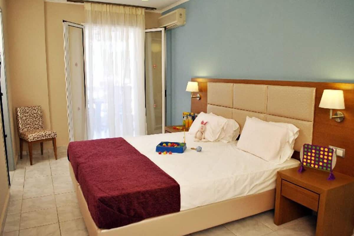 A hotel room with a bed, a chair, a nightstand, and a window with curtains.