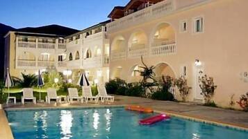 Una piscina al aire libre, sombrillas, sillones reclinables de piscina