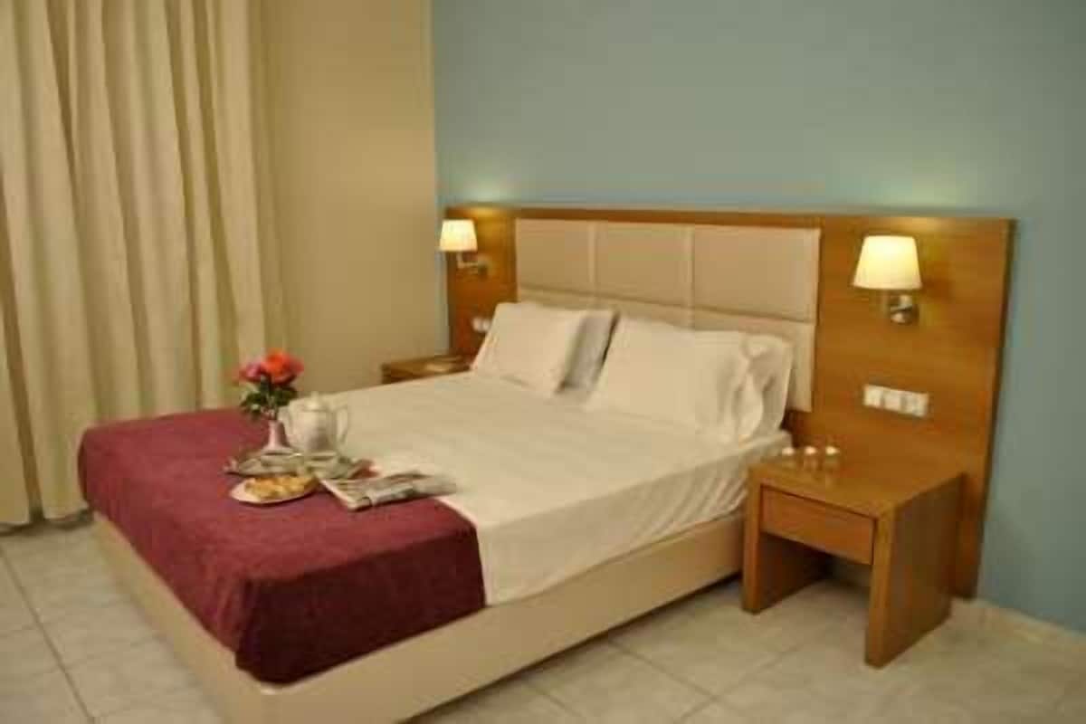 A hotel room with a bed, nightstands, a lamp, and a vase with flowers.
