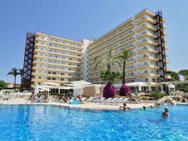 Un hotel con varios balcones, piscina y palmeras.