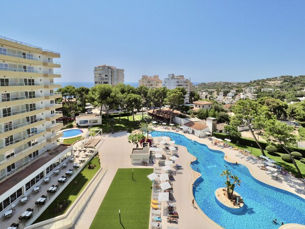 Un resort con una gran piscina, varias zonas de comedor y vistas al mar.