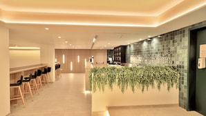 Un área de recepción moderna con una larga barra, varios taburetes y una pared cubierta de plantas verdes.