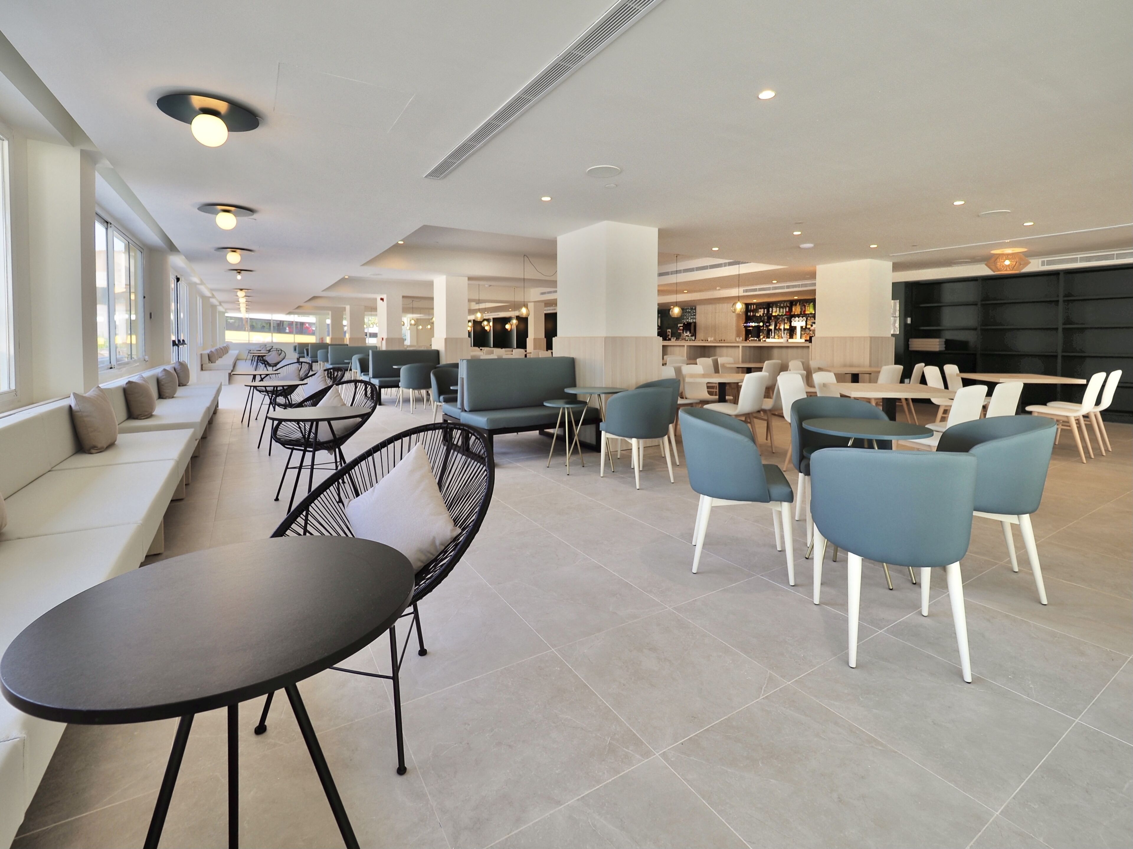 Zona pranzo moderna all'interno, con posti a sedere, tavoli e un'area bar.