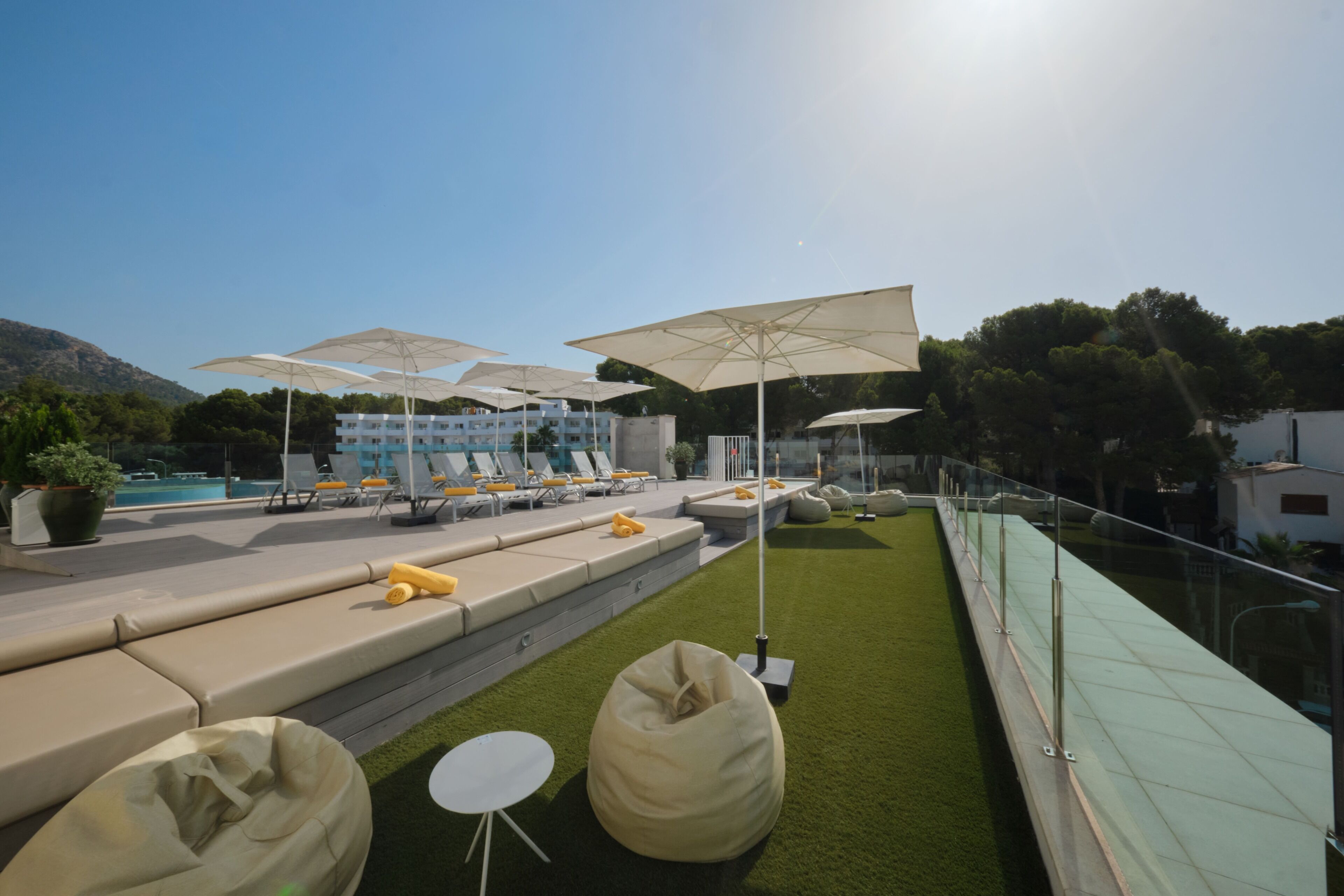 Terraza en la azotea con mobiliario exterior, sombrillas y una piscina al fondo.