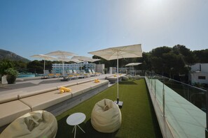 Terraza en la azotea con mobiliario exterior, sombrillas y una piscina al fondo.