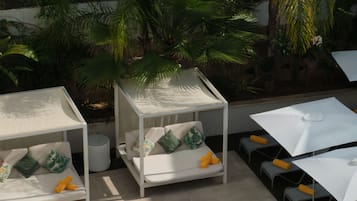Een terras op het dak met twee witte ligbedden, een tafeltje en een stoel.