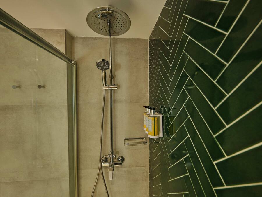 A shower area with a glass door, a handheld showerhead, and a wall-mounted control panel.