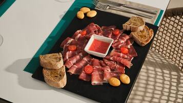 Un plato negro con varias carnes, pan y un recipiente pequeño con salsa.