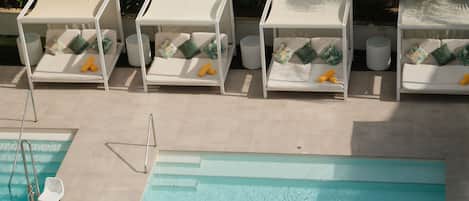 Una piscina al aire libre, sombrillas, sillones reclinables de piscina