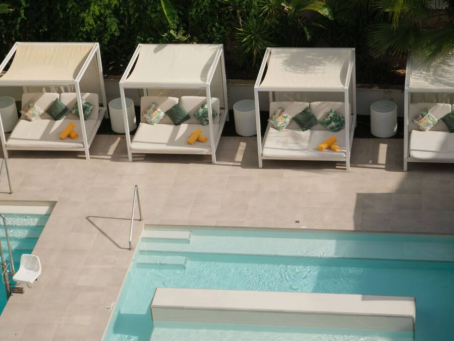 Una piscina al aire libre, sombrillas, sillones reclinables de piscina