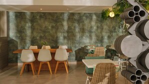 A dining area with a wooden table and chairs, a patterned wall, and a hanging light fixture. - BQ Paguera Boutique Hotel - Adults Only (Calvia)