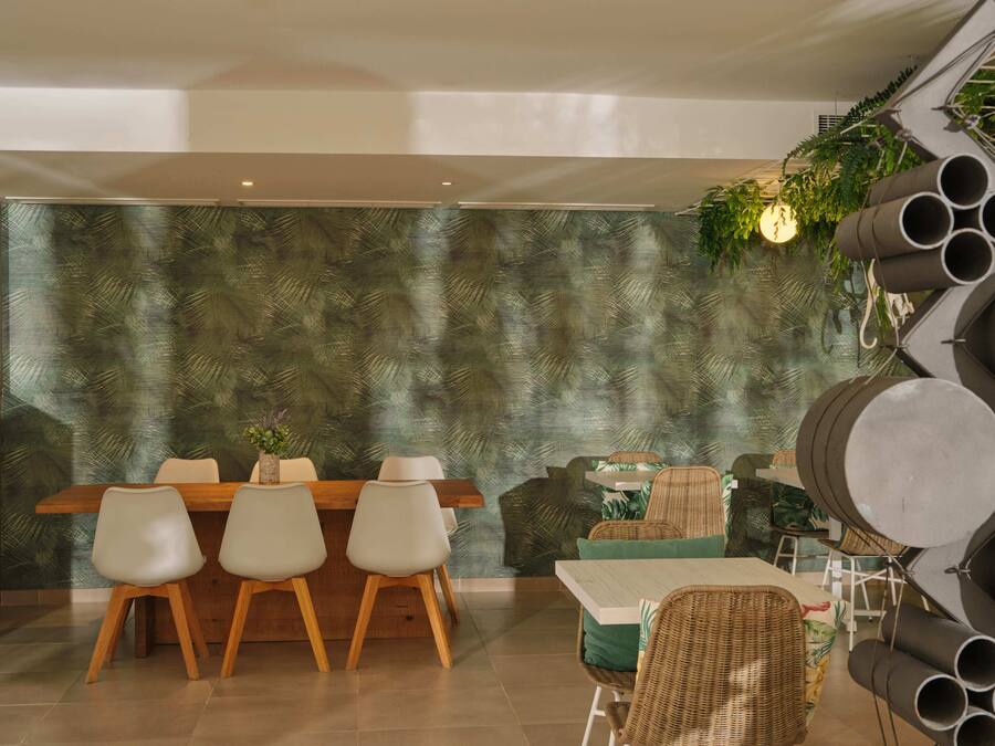 Un comedor con mesa y sillas de madera, pared con diseño y lámpara colgante.