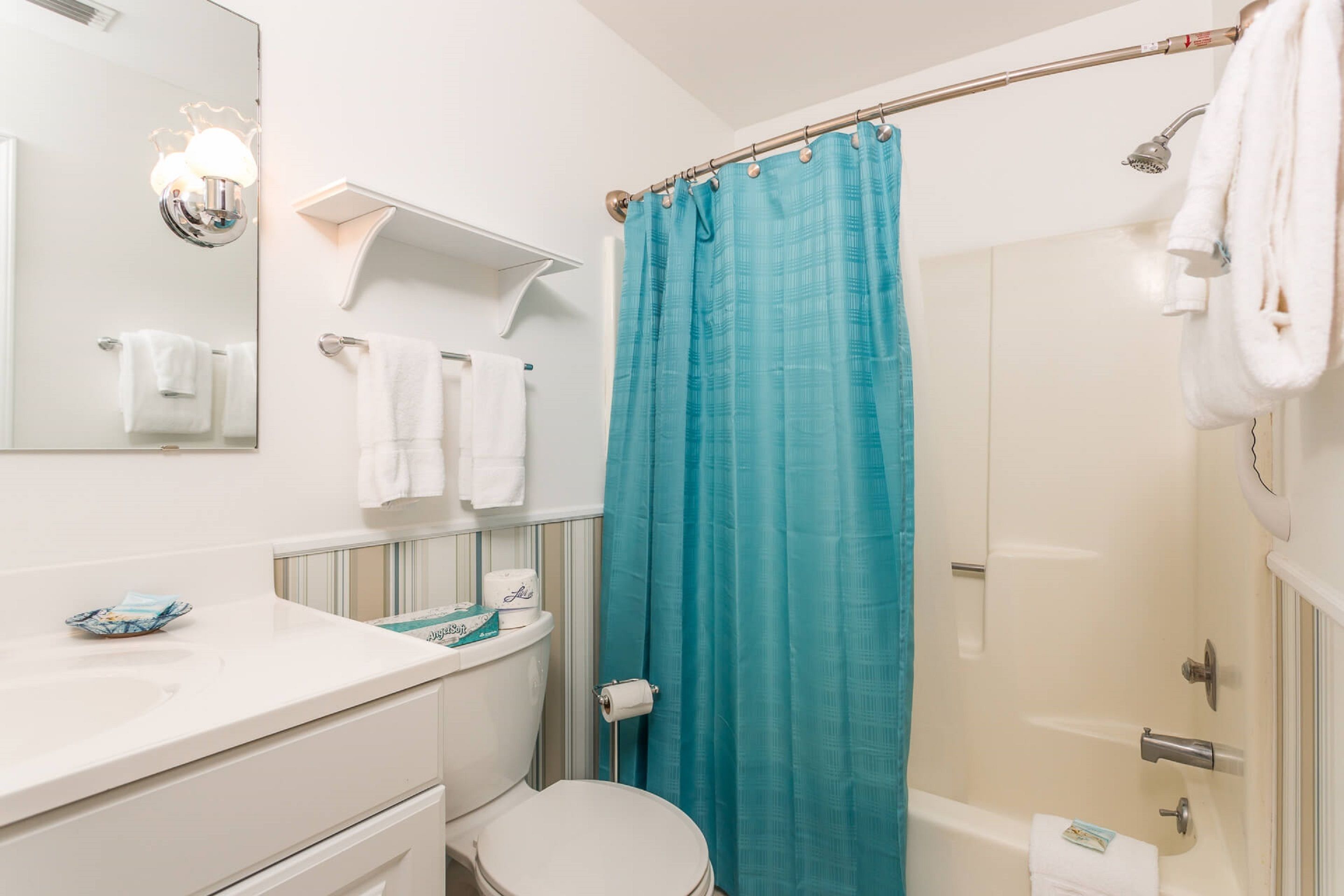 A bathroom with a white toilet, a sink, a mirror, and a shower curtain.