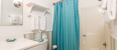 A bathroom with a white toilet, a sink, a mirror, and a shower curtain.