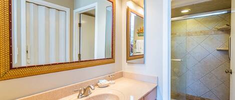 A bathroom with a large mirror, a sink, and a shower area.