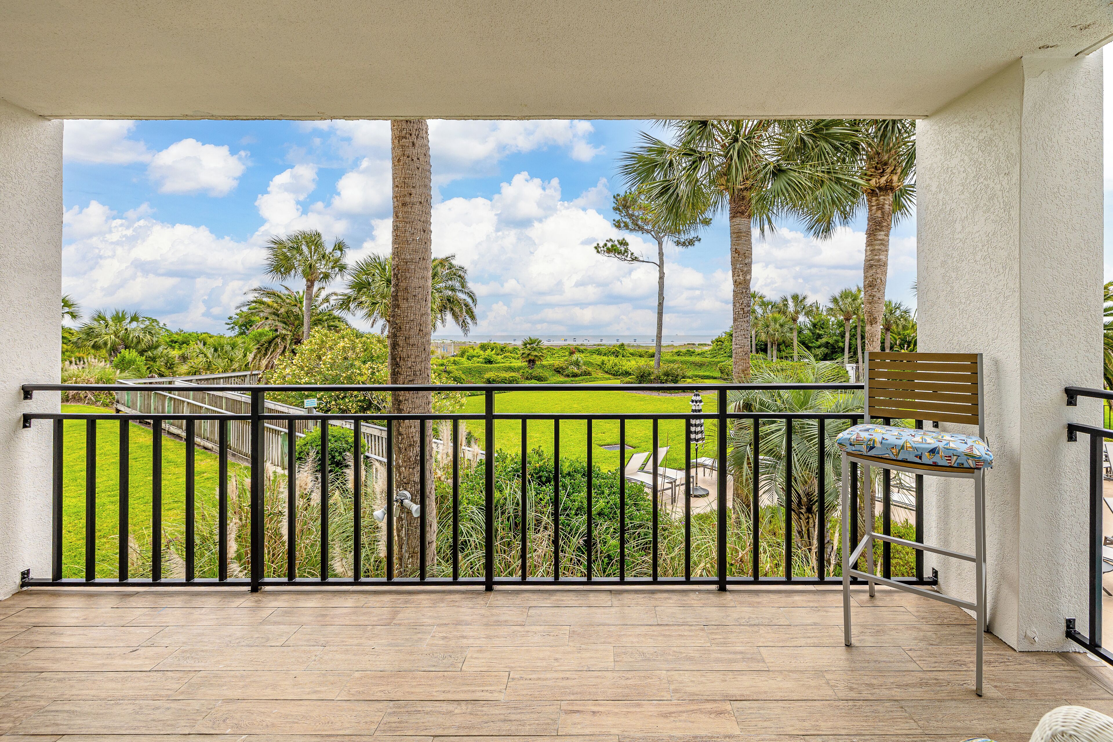 A balcony with a view of a green landscape and palm trees.