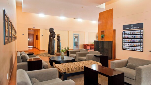Un hall d’hôtel avec des canapés, une table basse, une cheminée et un mur où sont affichées des brochures sur les chambres.