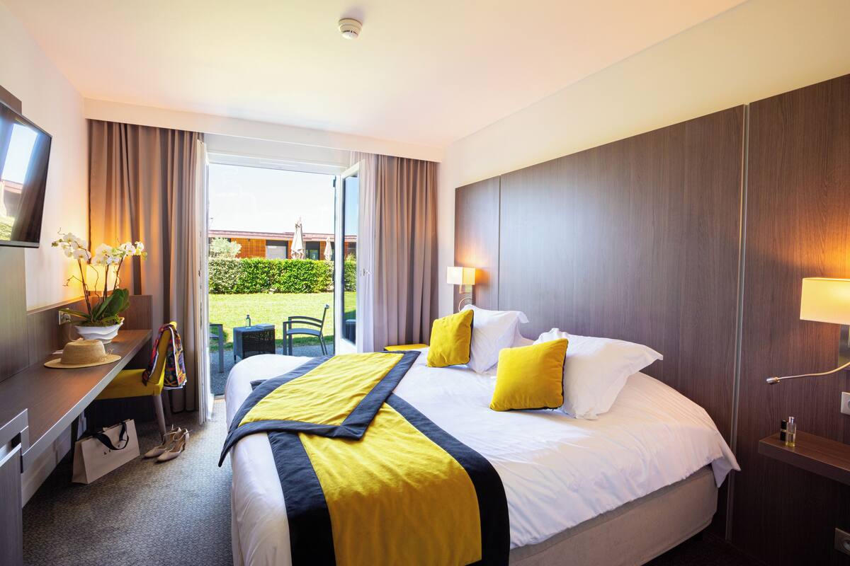 Hotelkamer met een bed, bureau, stoel, televisie en uitzicht op het omliggende landschap.