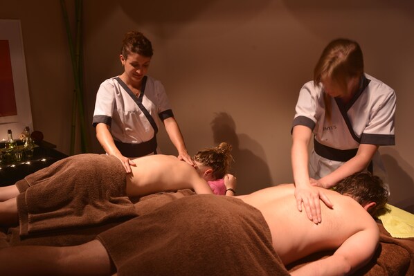 A massage therapy session in a dimly lit room with a massage table, towels, and a small table with bottles.