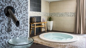 A bathroom with a glass bowl of ice, a wooden stool, a white planter, and a hot tub.