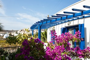 Un edificio blanco con contraventanas y una pérgola azules.