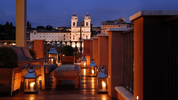 Una terraza en la azotea con suelo de madera, un sofá y varias linternas iluminadas.