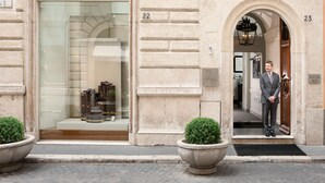 La entrada de un edificio con escaparate que muestra la marca Salvatore Ferragamo y puertas numeradas 22 y 23.