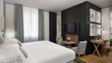 Quarto de hotel moderno com uma cama grande, uma escrivaninha, uma cadeira e uma televisão.