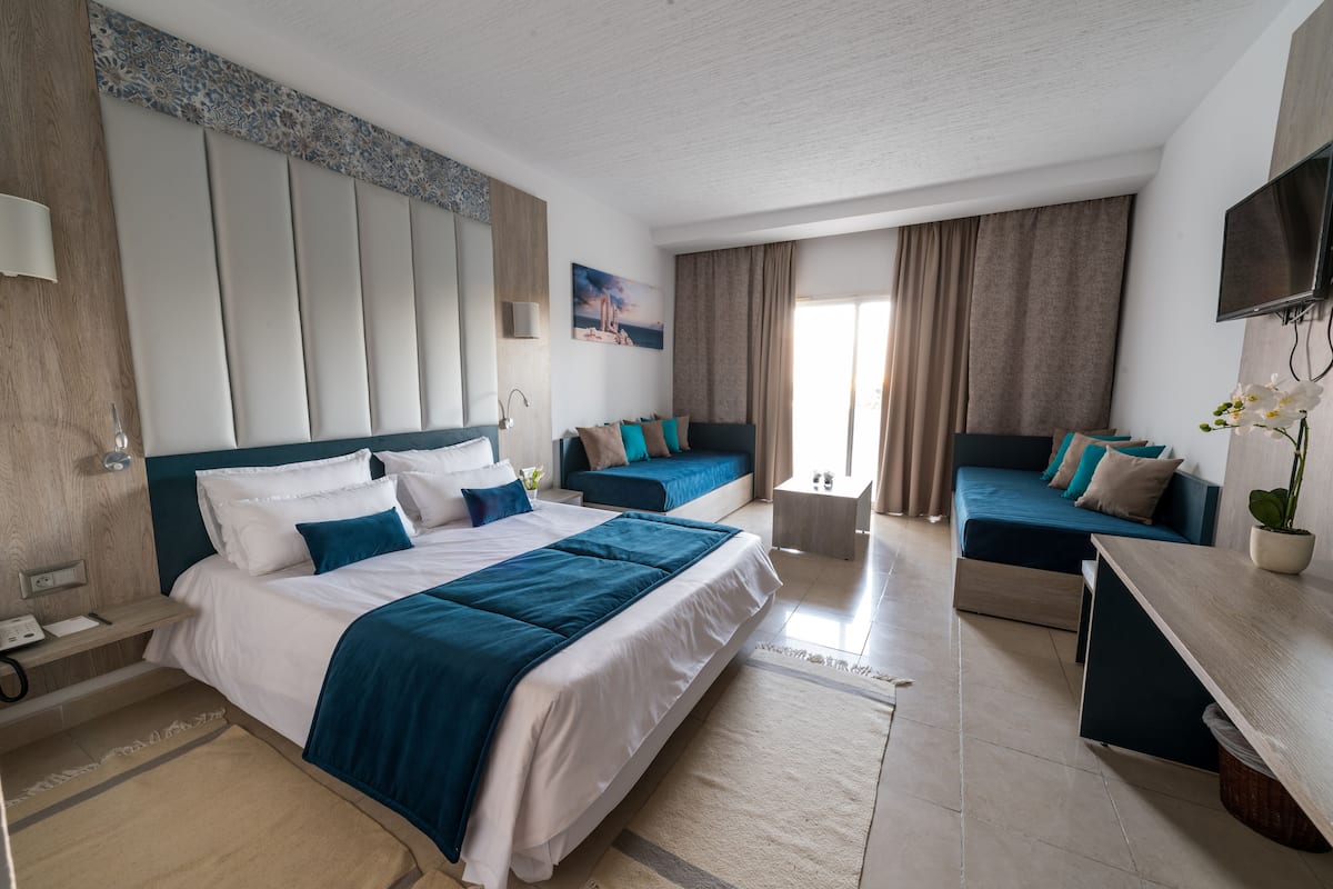 Una habitación de hotel moderna con una cama grande, un sofá, un escritorio y un televisor.