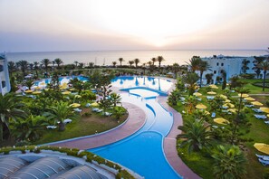 Un resort con una piscina grande, palmeras y vista al mar.