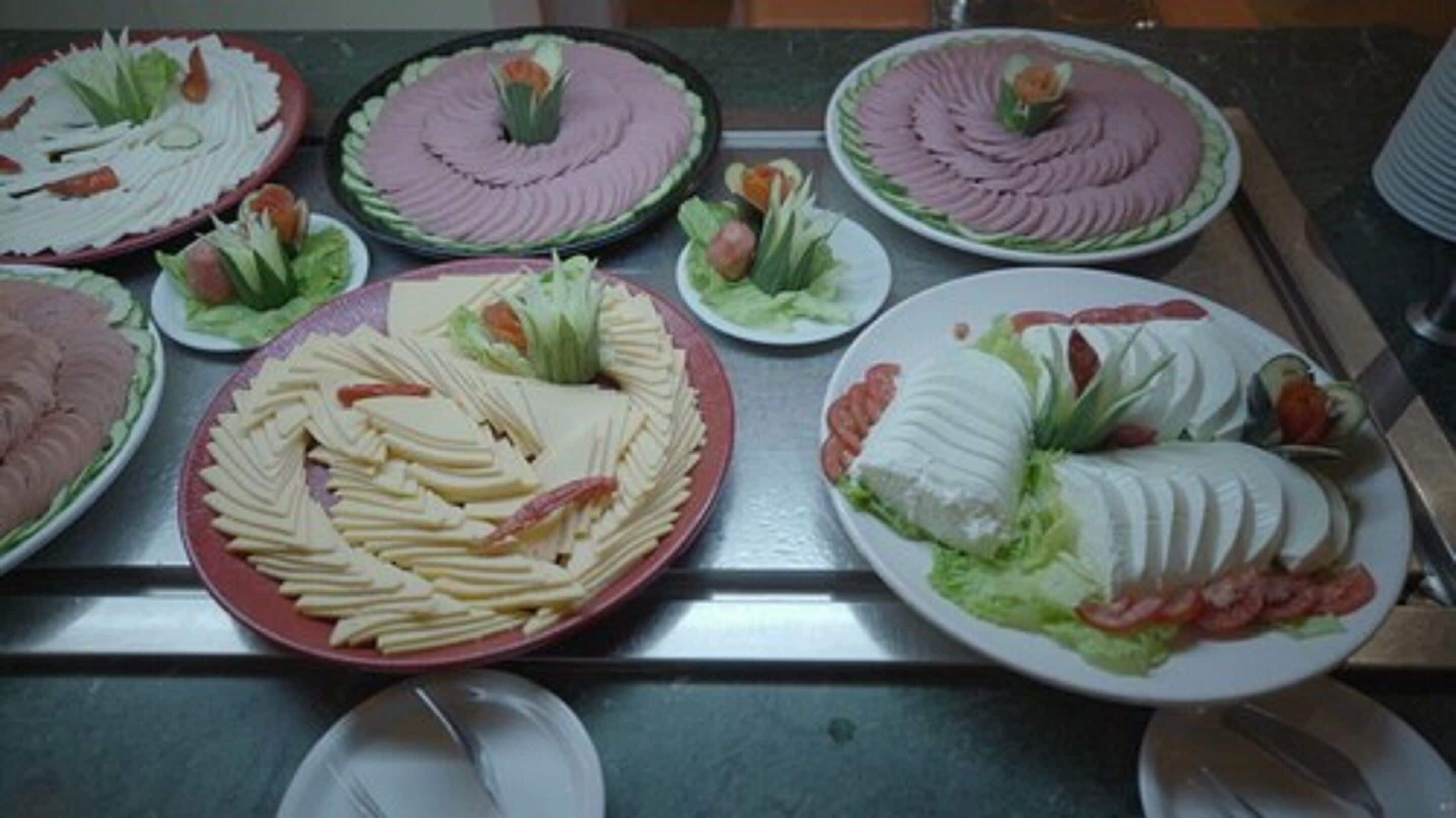 A buffet table with various food items arranged on plates.