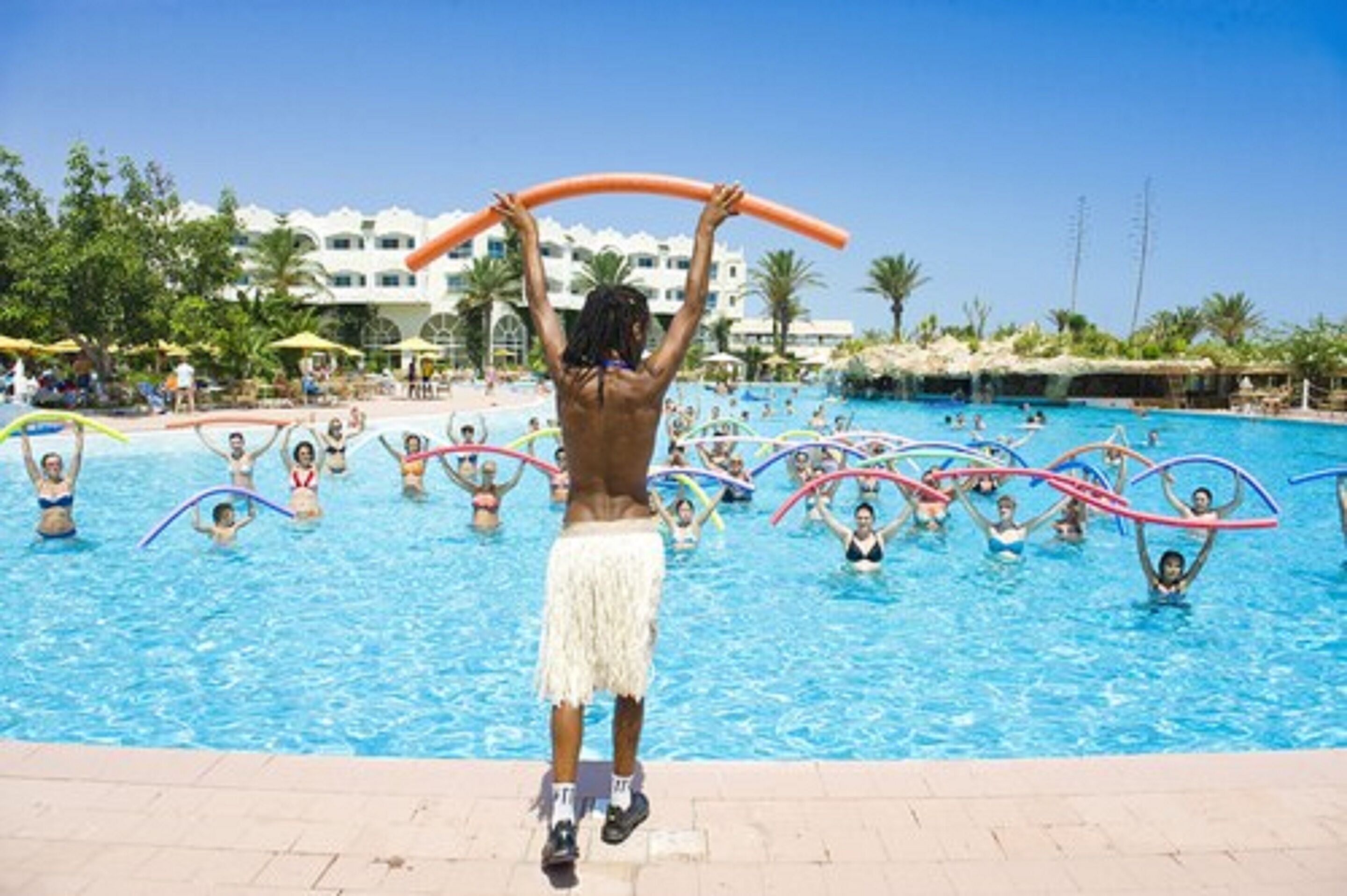 Une zone autour d’une piscine où des gens nagent et jouent avec des cerceaux.