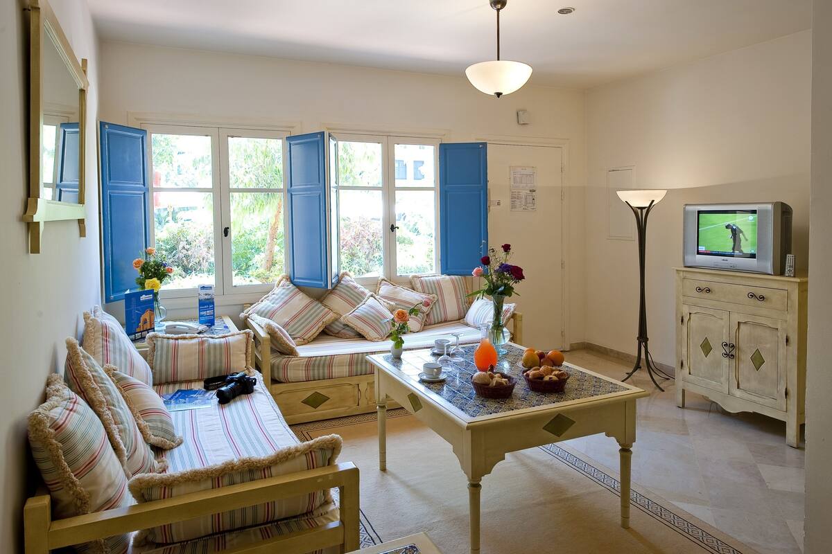 A cozy living room with a sofa, a coffee table, and a television.