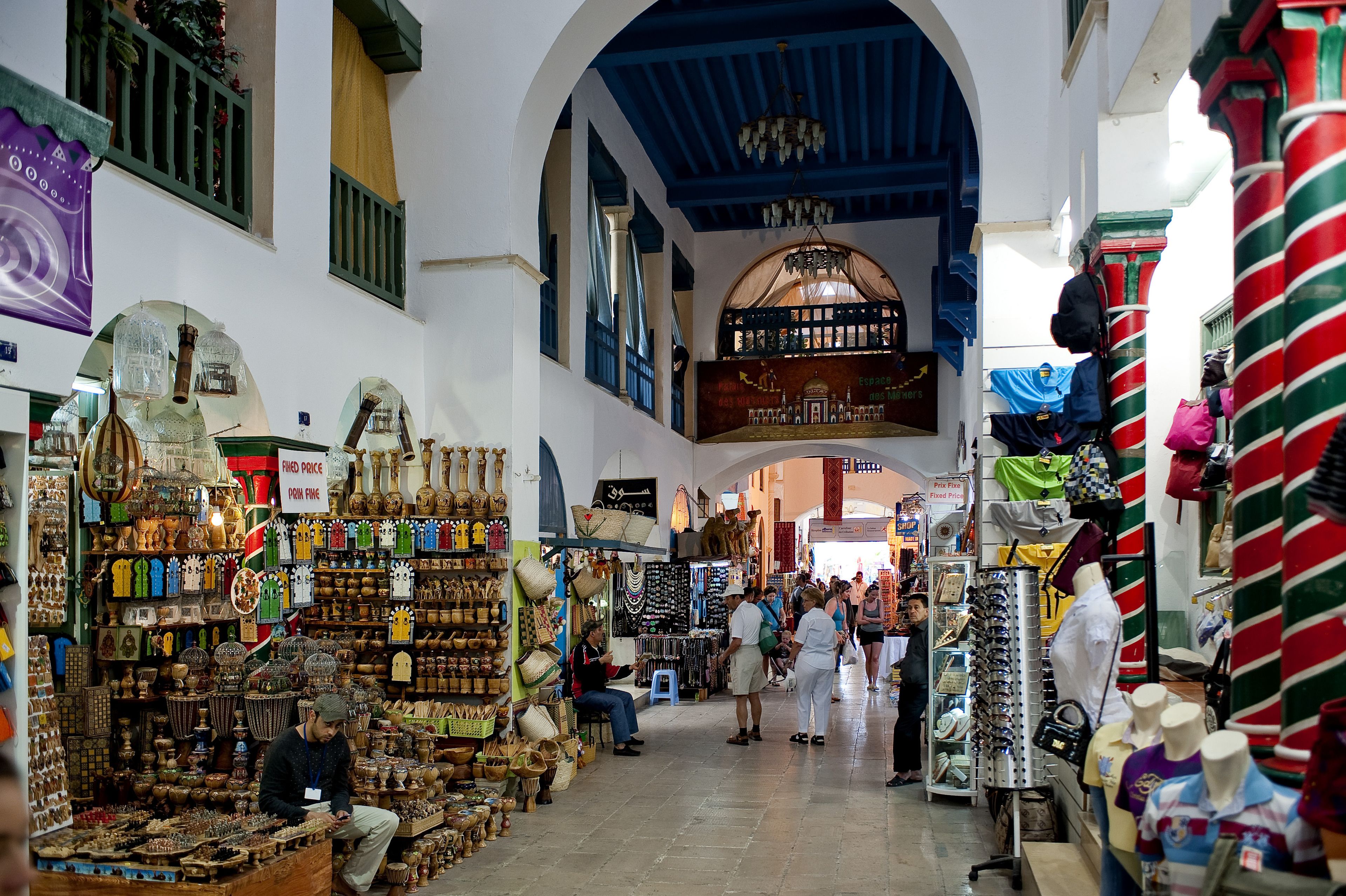 An indoor market with various stalls selling handicrafts and textiles.
