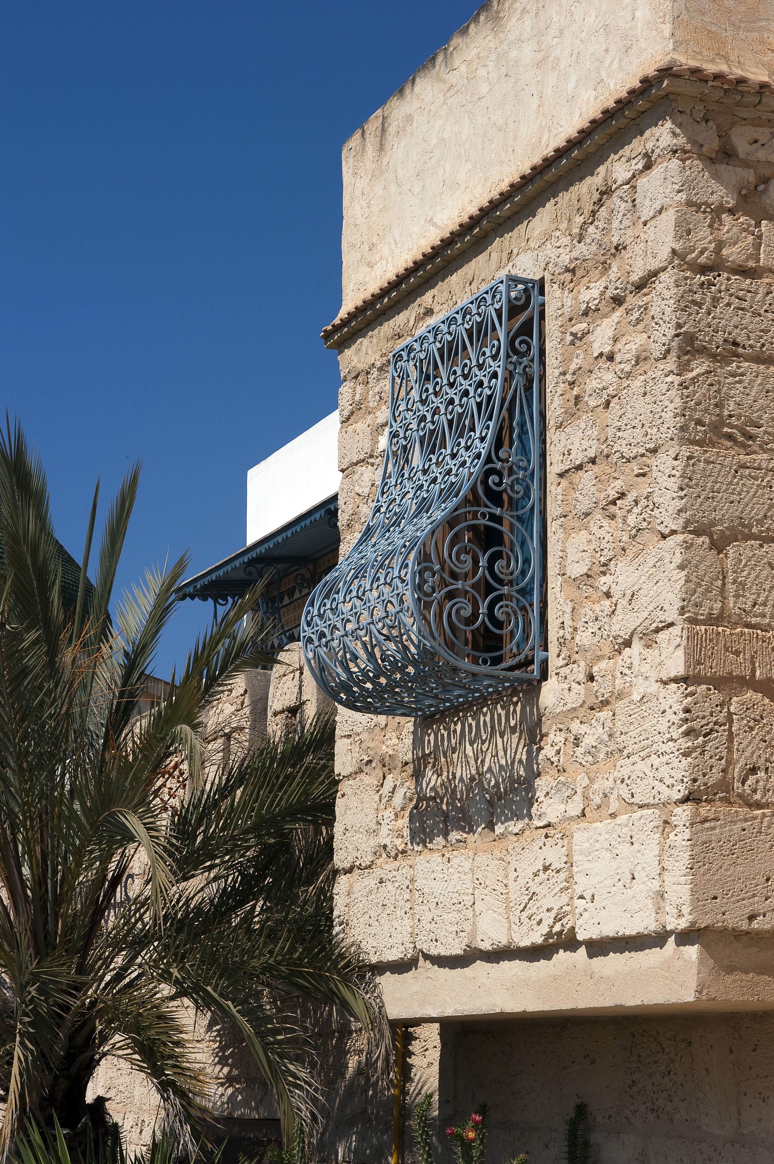 Un edificio con fachada de piedra y ventana de metal decorativa.