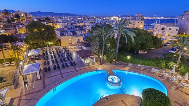 A swimming pool with sun loungers and a gym, surrounded by palm trees and overlooking a cityscape. - BQ Augusta Hotel (Palma de Mallorca)
