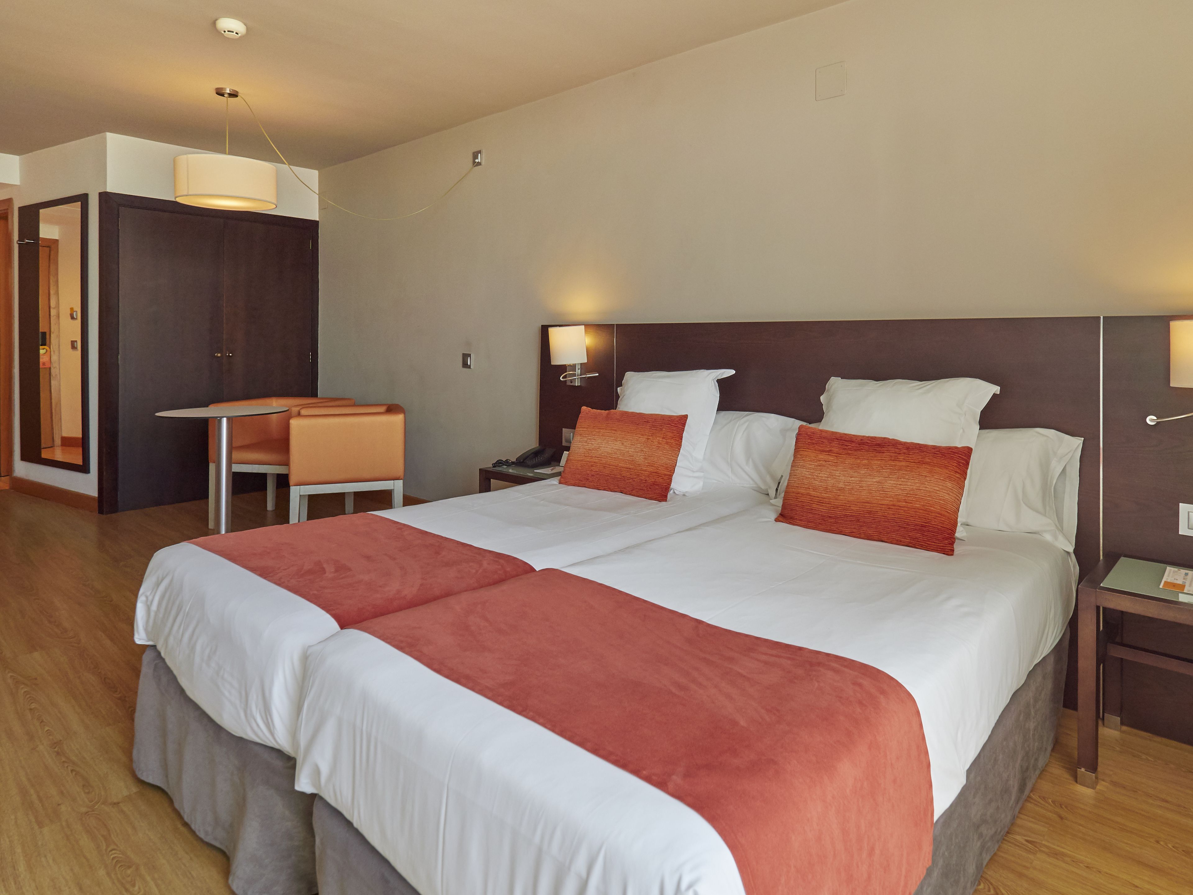 A hotel room with a large bed, two bedside tables, a desk, and a chair.