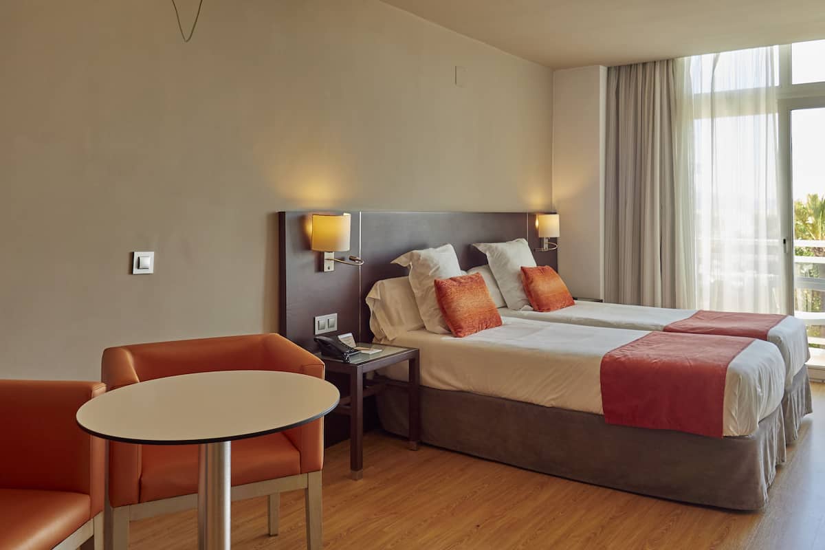 Una camera d'albergo con un letto matrimoniale, due comodini, una sedia e un tavolino.