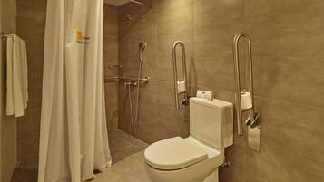 Un baño moderno con ducha, inodoro y barras de apoyo.