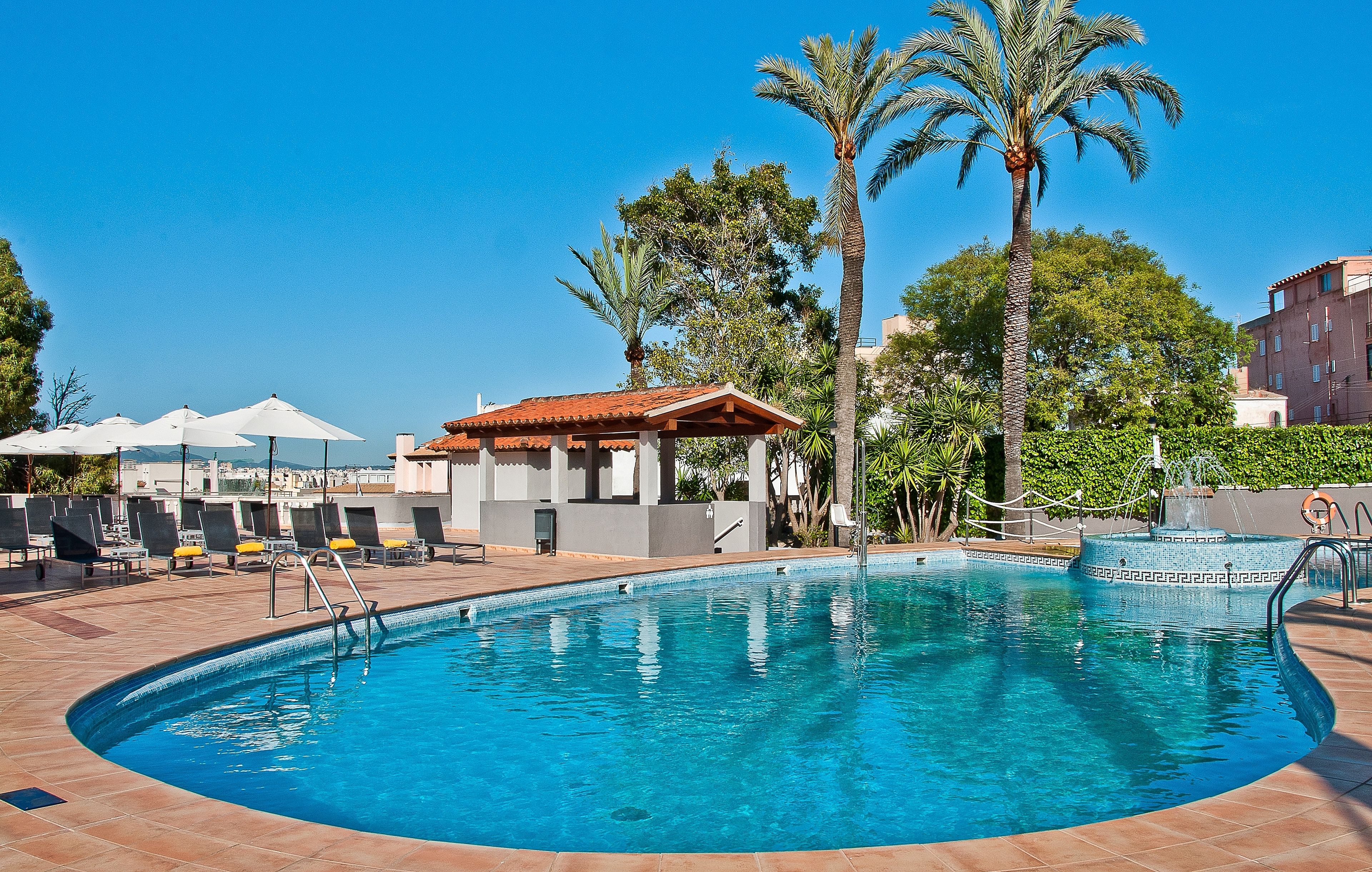 Een buitenzwembad, parasols bij het zwembad en ligstoelen