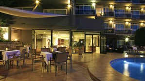 An outdoor dining area with tables and chairs, a pool, and a building with multiple balconies. - BQ Augusta Hotel (Palma de Mallorca)