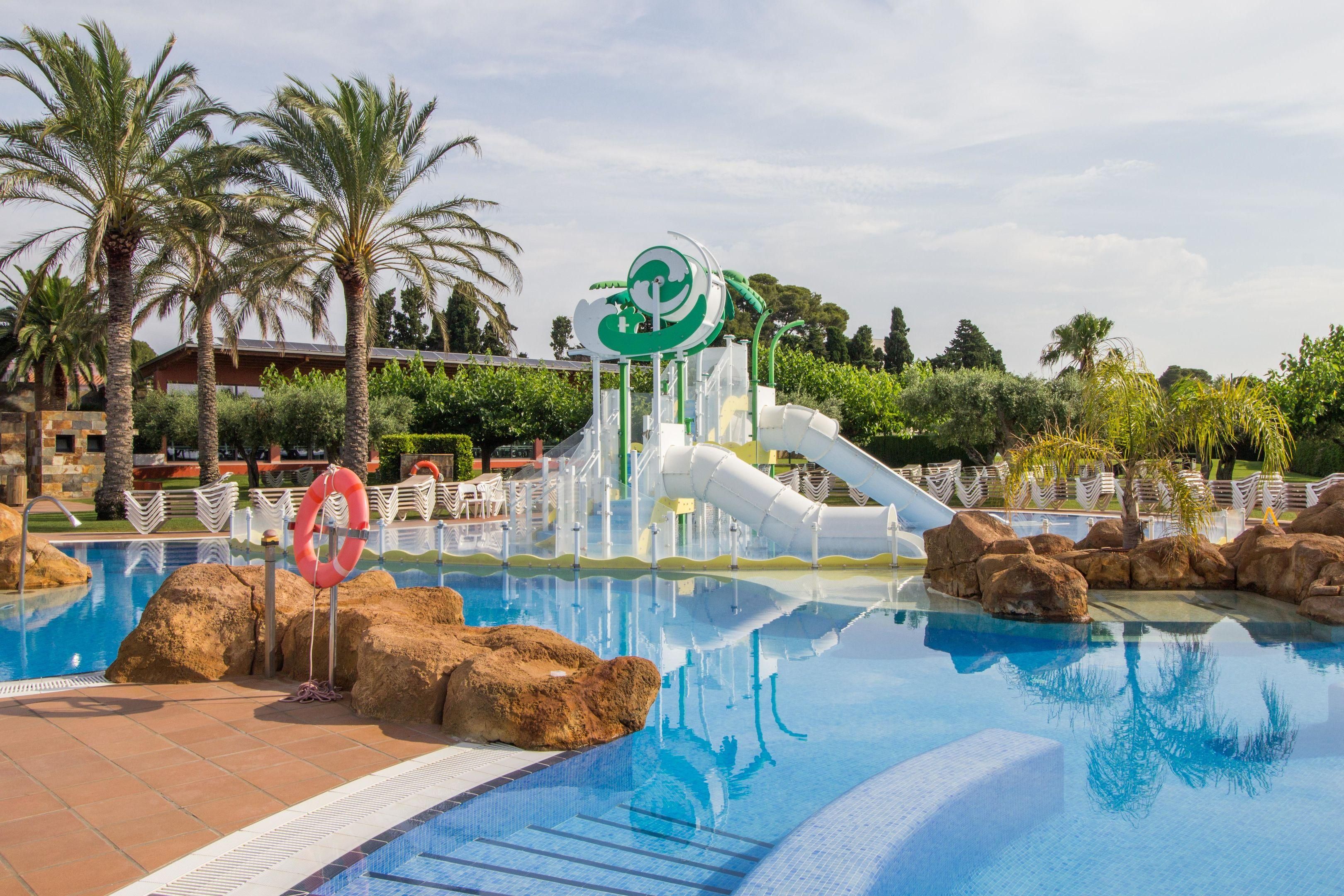 A swimming pool with a water slide, palm trees, and a lifebuoy.