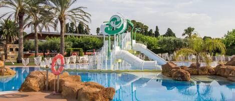 A swimming pool with a water slide, palm trees, and a lifebuoy.