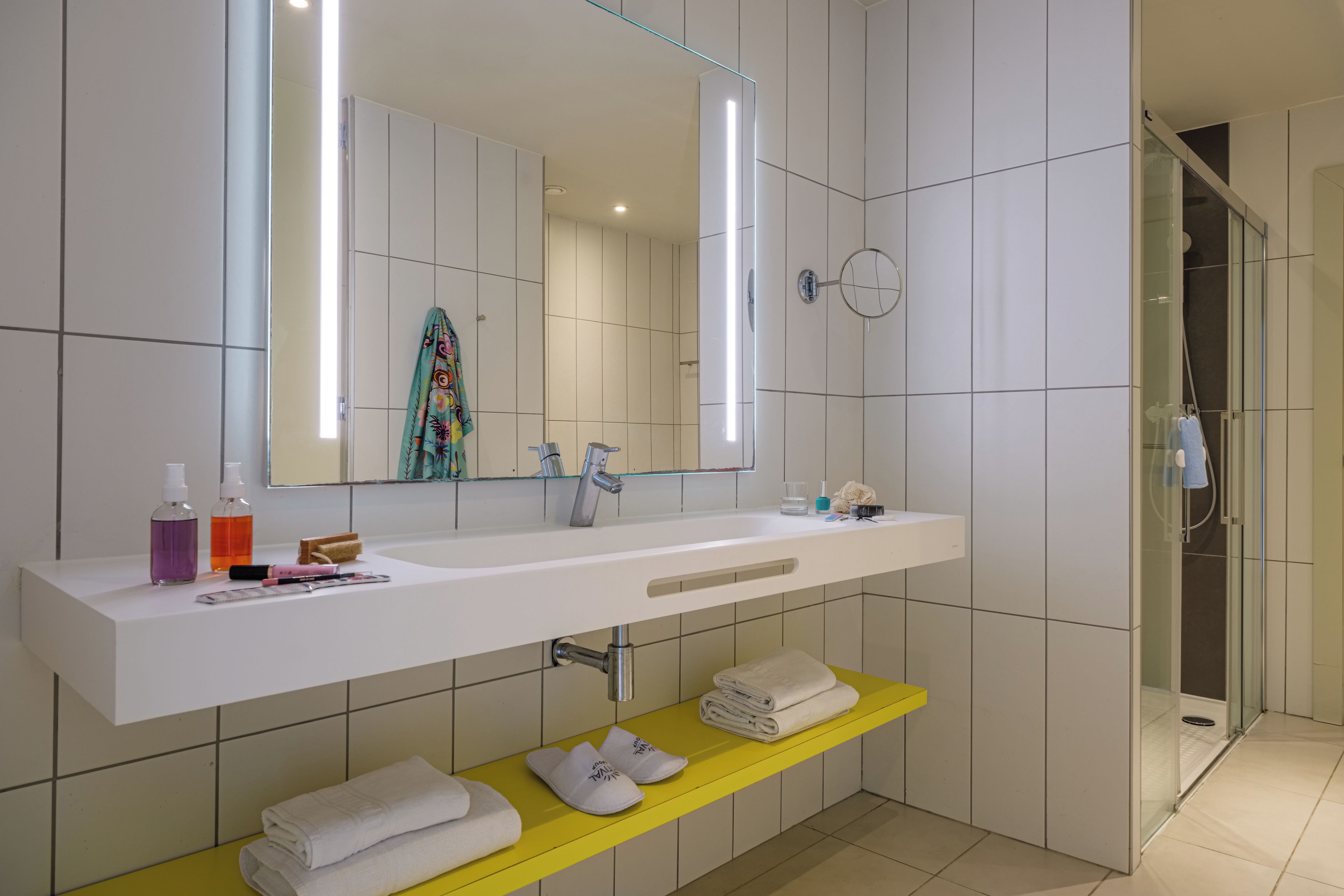 Un baño moderno con un lavabo blanco, un espejo y una zona de ducha.