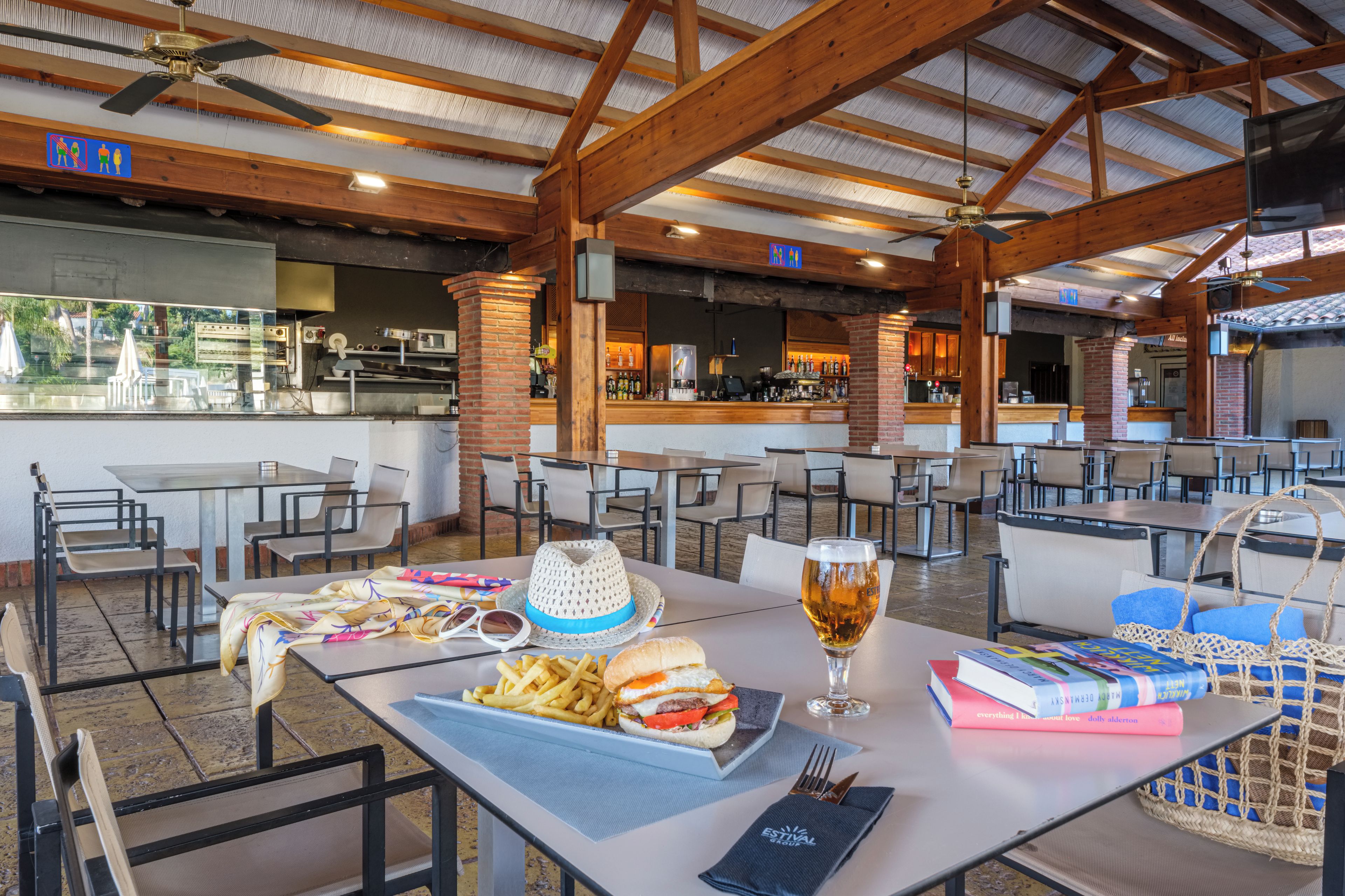 Un restaurante con mesas al aire libre, una zona de bar y vistas al exterior.